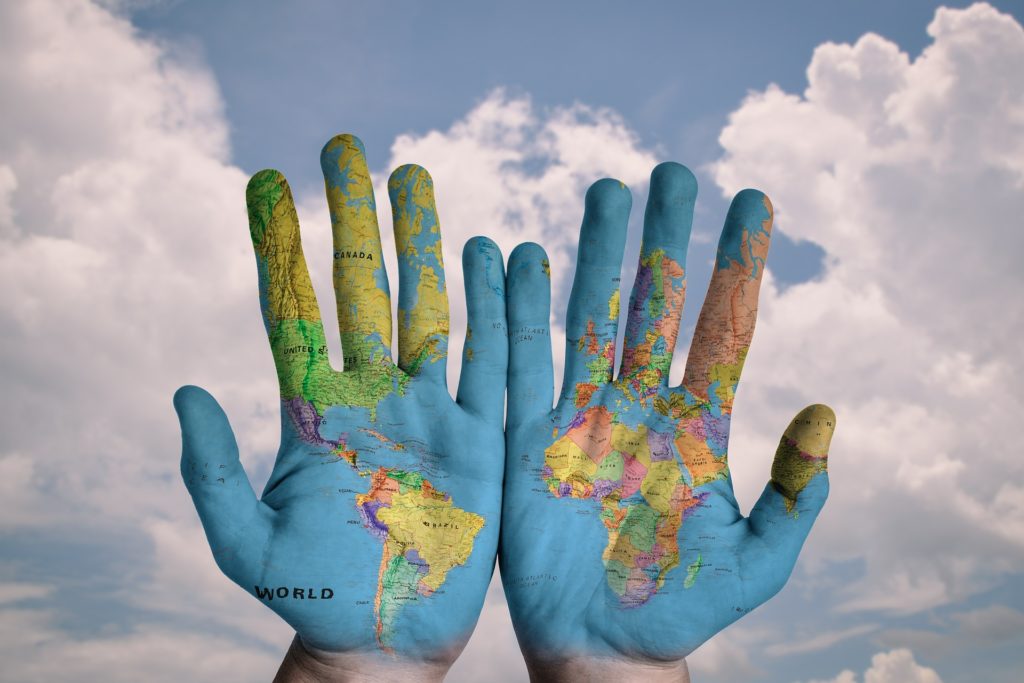 mani con dipinte la mappa geografica del mondo